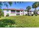 Back exterior of the property featuring glass doors, balconies, a large lawn, and palm trees at 507 Pine Hollow Cir # 507, Englewood, FL 34223