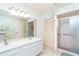 Bathroom with double sinks, a spacious closet, a large mirror, and a glass-enclosed shower at 6206 Marcum St, Englewood, FL 34224