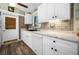 Bright kitchen featuring white cabinets, brick backsplash, wood-look flooring, and a black sink at 6417 Klaus Ct, Port Charlotte, FL 33981