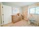 Bright Bedroom features light wood flooring, floral wallpaper and a changing table with ample storage at 7234 Mamouth St, Englewood, FL 34224