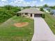 Single-story home with lush landscaping, long driveway, and charming curb appeal at 7393 Mamouth St, Englewood, FL 34224