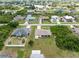 An aerial view showcasing houses on large lots with mature trees and landscaping near a lake at 7393 Mamouth St, Englewood, FL 34224