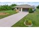 Single-story home with lush lawn, mature landscaping, and an extended driveway at 7393 Mamouth St, Englewood, FL 34224