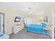 Bright bedroom featuring a ceiling fan, dresser with mounted TV, and a bed with a blue quilt at 878 Fawnspring Ct, Englewood, FL 34223