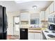 Functional kitchen with white cabinetry, black appliances, and wood-look flooring and a back door at 878 Fawnspring Ct, Englewood, FL 34223