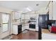 Functional kitchen with white cabinetry, black appliances, and wood-look flooring at 878 Fawnspring Ct, Englewood, FL 34223