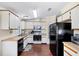 Bright kitchen featuring white cabinets, black appliances, and wood-look flooring at 878 Fawnspring Ct, Englewood, FL 34223