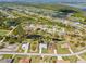 A wide aerial view shows a neighborhood near a golf course and a winding canal amid lush greenery at 116 Tournament Rd, Rotonda West, FL 33947