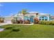 Charming single-story home with a well-manicured lawn, colorful landscaping, and a vibrant blue front door at 116 Tournament Rd, Rotonda West, FL 33947