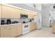 Well-lit kitchen with light wood cabinets, white appliances, and tile floors at 116 Tournament Rd, Rotonda West, FL 33947