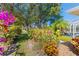 Lush backyard with vibrant flowers and mature trees creates a serene outdoor space at 116 Tournament Rd, Rotonda West, FL 33947