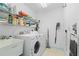 Functional laundry room with modern washer and dryer, storage shelves, and utility sink at 116 Tournament Rd, Rotonda West, FL 33947