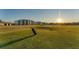 Picturesque golf course with a golf bag on the green, set against a backdrop of modern buildings and a setting sun at 12470 Wellen Golf St # 108, Venice, FL 34293