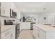 Modern white kitchen with stainless steel appliances, light countertops and a view into the living area at 12470 Wellen Golf St # 108, Venice, FL 34293