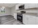 Kitchen with white cabinets, stainless steel appliances, gray plank flooring, and granite countertops at 13529 Boatbill Ln, Port Charlotte, FL 33981