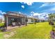 Wide view of backyard showing well-maintained lawn, landscaping, lake, and covered patios at 13859 Vadini St, Venice, FL 34293
