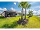 Rear of home with covered patio, beautiful green grass, lake, and palm tree landscaping at 13859 Vadini St, Venice, FL 34293