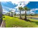 View of backyard including green grass, lake, palm trees, and beautiful landscaping at 13859 Vadini St, Venice, FL 34293
