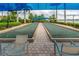 Bocce ball court with seating under a blue shade, surrounded by palm trees and landscaping at 13859 Vadini St, Venice, FL 34293