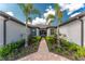 Inviting home entrance with a brick pathway, lush landscaping, and symmetrical palm trees enhancing the curb appeal at 13859 Vadini St, Venice, FL 34293