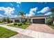 Attractive home showcasing a brick driveway, lush landscaping, and a symmetrical facade with a well-maintained lawn at 13859 Vadini St, Venice, FL 34293