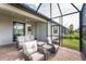 View of the screened-in patio with wicker chairs, sofa, and table with access to the home at 13859 Vadini St, Venice, FL 34293