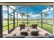 View of patio from inside showing outdoor chairs and ottomans with a view of the lawn and lake at 13859 Vadini St, Venice, FL 34293