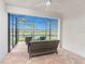 Screened-in patio with brick floor, ceiling fan, and wicker furniture overlooking lawn and lake at 13859 Vadini St, Venice, FL 34293