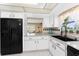 Kitchen featuring white cabinets, a black refrigerator, a double basin sink, and lots of light at 146 Rotonda Cir, Rotonda West, FL 33947