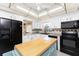 Bright kitchen featuring white cabinets, black appliances, and a light blue movable island at 146 Rotonda Cir, Rotonda West, FL 33947