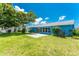 Exterior view of home showcasing backyard with patio, lush lawn and mature landscaping at 23 Bunker Cir, Rotonda West, FL 33947