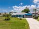 Charming blue home featuring a lush lawn, gray roof, stone accents, and well-maintained landscaping at 23 Bunker Cir, Rotonda West, FL 33947