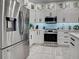 Modern kitchen showcasing stainless steel refrigerator, appliances, white cabinetry, granite countertops, and tile floors at 2590 Tarpon Cove Dr # 811, Punta Gorda, FL 33950