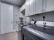 Bright laundry room with gray washer/dryer, white cabinetry, sink, granite countertops, and a door to another room at 2590 Tarpon Cove Dr # 811, Punta Gorda, FL 33950