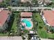 Overhead view of community pool and adjacent shaded patio, surrounded by green landscaping and nearby houses at 2590 Tarpon Cove Dr # 811, Punta Gorda, FL 33950