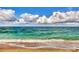 Gentle ocean waves rolling onto a sandy beach under a bright blue sky with fluffy white clouds at 2700 N Beach Rd # B205, Englewood, FL 34223