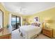 Sunlit bedroom with a coastal decor, ceiling fan, and sliding glass doors to a private balcony at 2700 N Beach Rd # B205, Englewood, FL 34223