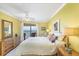 Bright bedroom with coastal decor, ceiling fan, and sliding glass doors to the balcony with ocean views at 2700 N Beach Rd # B205, Englewood, FL 34223