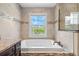 Bright bathroom featuring a soaking tub with tile surround and a view to the outside at 2758 Morrietta Ln, North Port, FL 34286