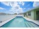 Inviting in-ground pool with crystal-clear water, a white fence, and a partial view of the house under a sunny sky at 279 Mark Twain Ln, Rotonda West, FL 33947