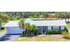 Single-story home with white paint, gray roof, lush landscaping, an attached garage and a well-manicured lawn at 305 E Wentworth Cir, Englewood, FL 34223