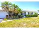 Inviting single-Gathering home features neat landscaping, mature palms, and a charming front entrance with an arched gate at 305 E Wentworth Cir, Englewood, FL 34223