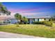 Charming single-story home with well-maintained lawn, lush landscaping, and a driveway leading to an attached garage at 305 E Wentworth Cir, Englewood, FL 34223