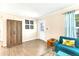 Living room with wood-look flooring, bright window, teal couch, and rustic wood cabinet at 305 E Wentworth Cir, Englewood, FL 34223
