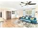 Inviting living room with sleek wood floors, teal furniture, a rustic cabinet, and large window at 305 E Wentworth Cir, Englewood, FL 34223