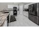 Modern kitchen featuring white cabinetry, black appliances, granite countertops, and tile flooring at 3695 Waffle Ter, North Port, FL 34286