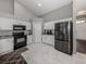 Modern kitchen featuring white cabinetry, black appliances, granite countertops, and tile flooring at 3695 Waffle Ter, North Port, FL 34286