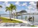 Waterfront home features a covered boat lift, dock, and seating with lush landscaping and clear blue skies at 565 Green Dolphin S Dr, Placida, FL 33946