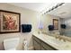 Cozy bathroom with a decorative picture, a toilet, and a vanity featuring a marble countertop and an oval mirror with lights at 5700 Gulf Shores Dr # B-137, Boca Grande, FL 33921