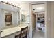 Bathroom vanity featuring drawers and a marble top, a walk-in closet with built-in shelving, and a mirror with lights at 5700 Gulf Shores Dr # B-137, Boca Grande, FL 33921
